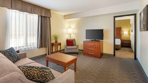A hotel room with a sofa, a coffee table, a TV, a desk, and a lamp. - Best Western Chicago - Downers Grove (Downers Grove)