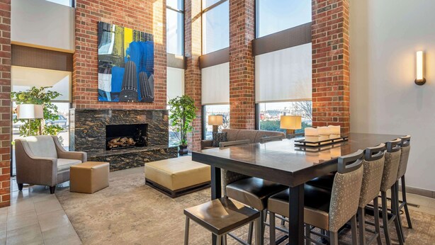 A spacious interior with a large dining table, comfortable seating, a fireplace, and large windows offering views of the city. - Best Western Chicago - Downers Grove (Downers Grove)