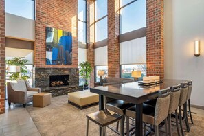 A spacious interior with a large dining table, comfortable seating, a fireplace, and large windows offering views of the city. - Best Western Chicago - Downers Grove (Downers Grove)