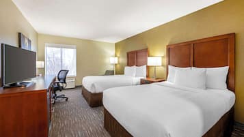 Une chambre d’hôtel avec deux lits, un bureau avec une télévision et une chaise.