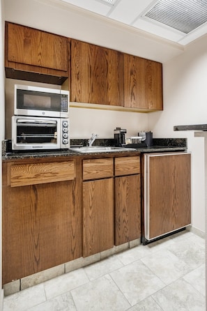 A kitchen with wooden cabinets, a microwave, an oven, a sink, and a refrigerator.