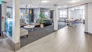 Um espaço de escritório moderno com área de reuniões, assentos de lounge e um balcão de recepção.