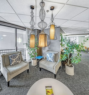 A modern lounge area with patterned sofas, a coffee table, and hanging pendant lights.