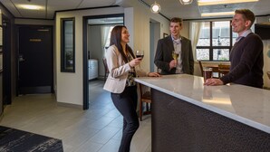 A modern hotel lobby with a reception desk, a seating area, and a view of the outdoors through large windows. - The Voyager Inn (Anchorage)