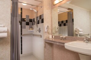 A modern bathroom with a shower, a sink, and a mirror.