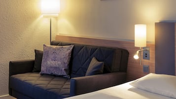 Een hotelkamer met een bed, een sofa, een wandlamp en een schilderij.