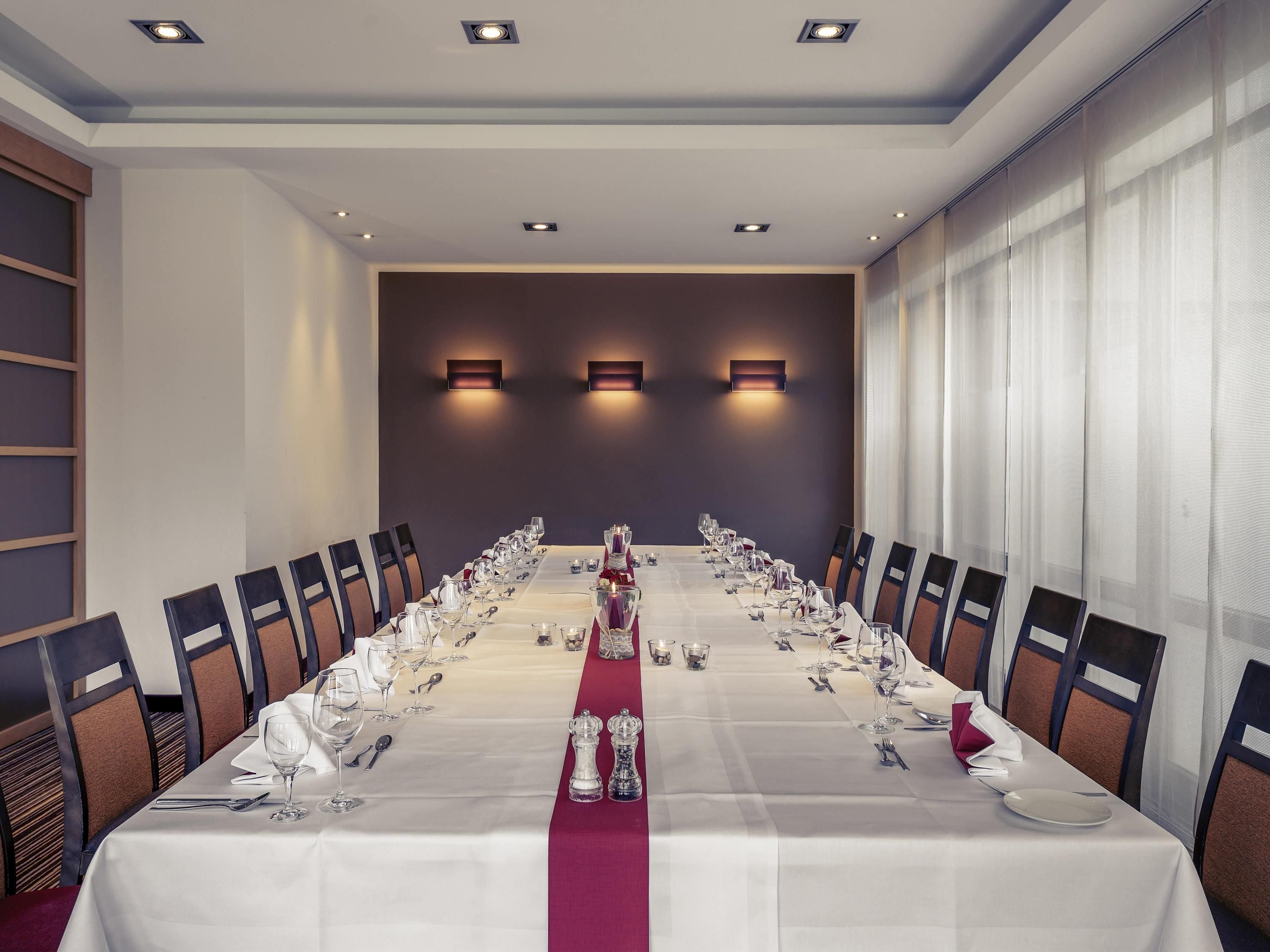 A conference room with a long table, chairs, and wall-mounted lighting.