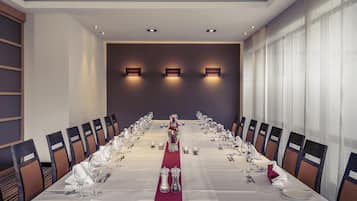 A conference room with a long table, chairs, and wall-mounted lighting.