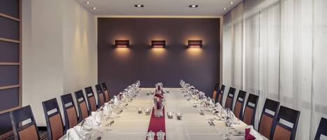 A conference room with a long table, chairs, and wall-mounted lighting.