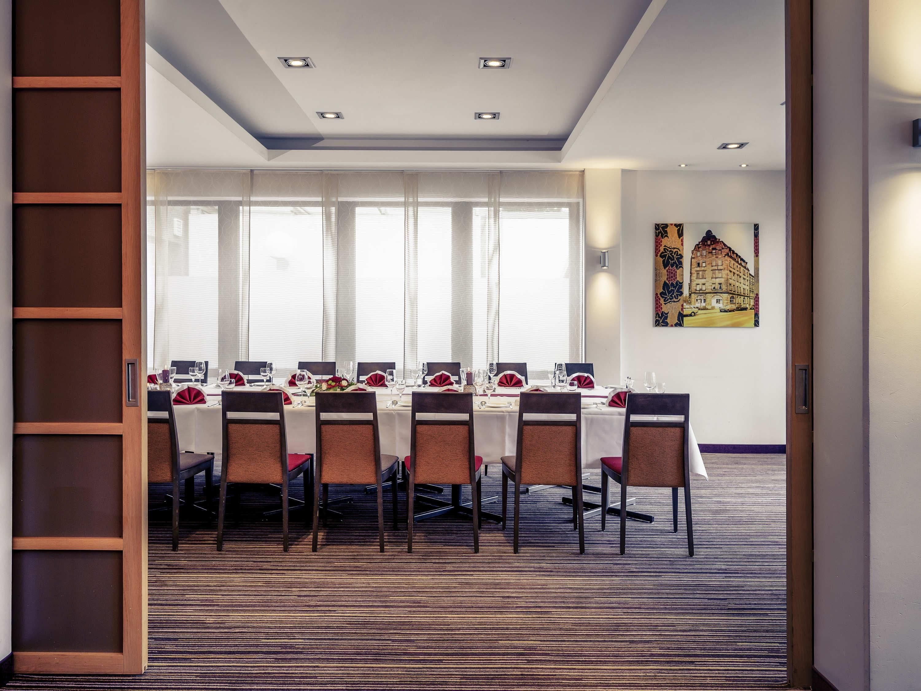 A conference room with a long table, chairs, and a carpeted floor.