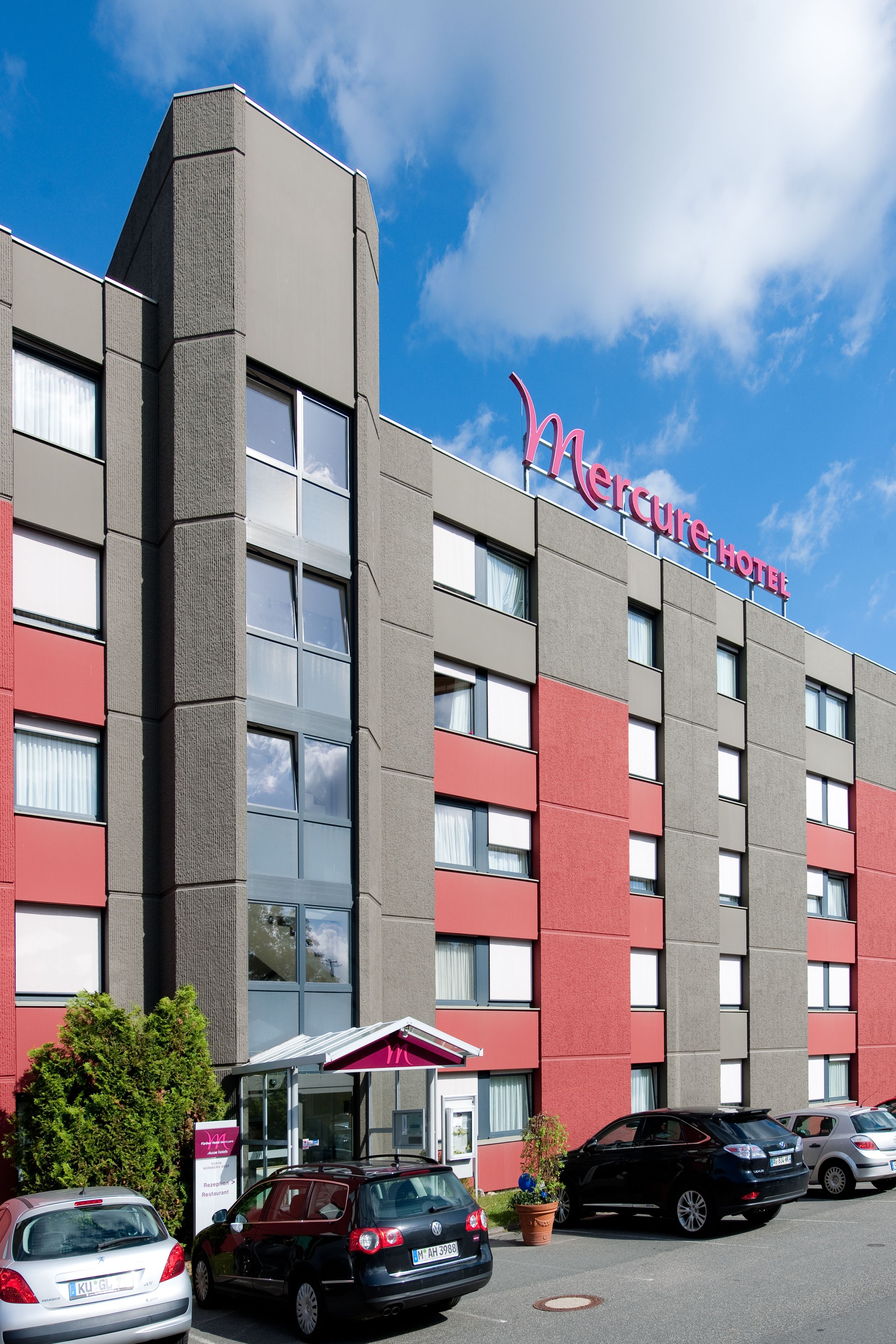 A hotel building with a red and grey facade, multiple windows, and a sign reading "Mercure Hotel".