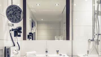 Un baño moderno con un espejo grande, un secador de pelo, una toalla, un lavamanos y una ducha.