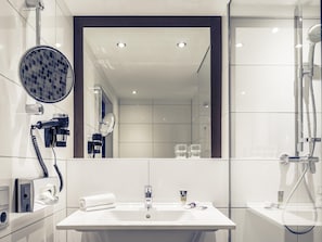 Un baño moderno con un espejo grande, un secador de pelo, una toalla, un lavamanos y una ducha.