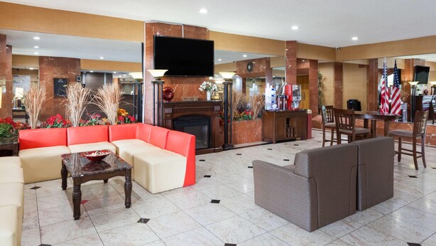 Un vestíbulo de hotel con un sof á rojo, un sofá beige, una mesa de centro de madera y un sofá gris.