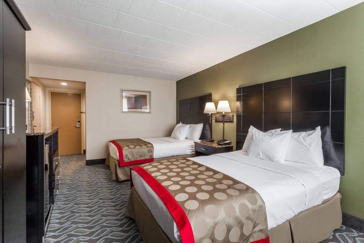 A hotel room with two beds, a desk, and a nightstand.