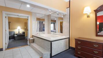 A hotel bathroom with a large mirror, a double sink, and a wooden dresser.