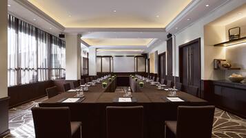 A conference room with a long table, chairs, and a projector screen.