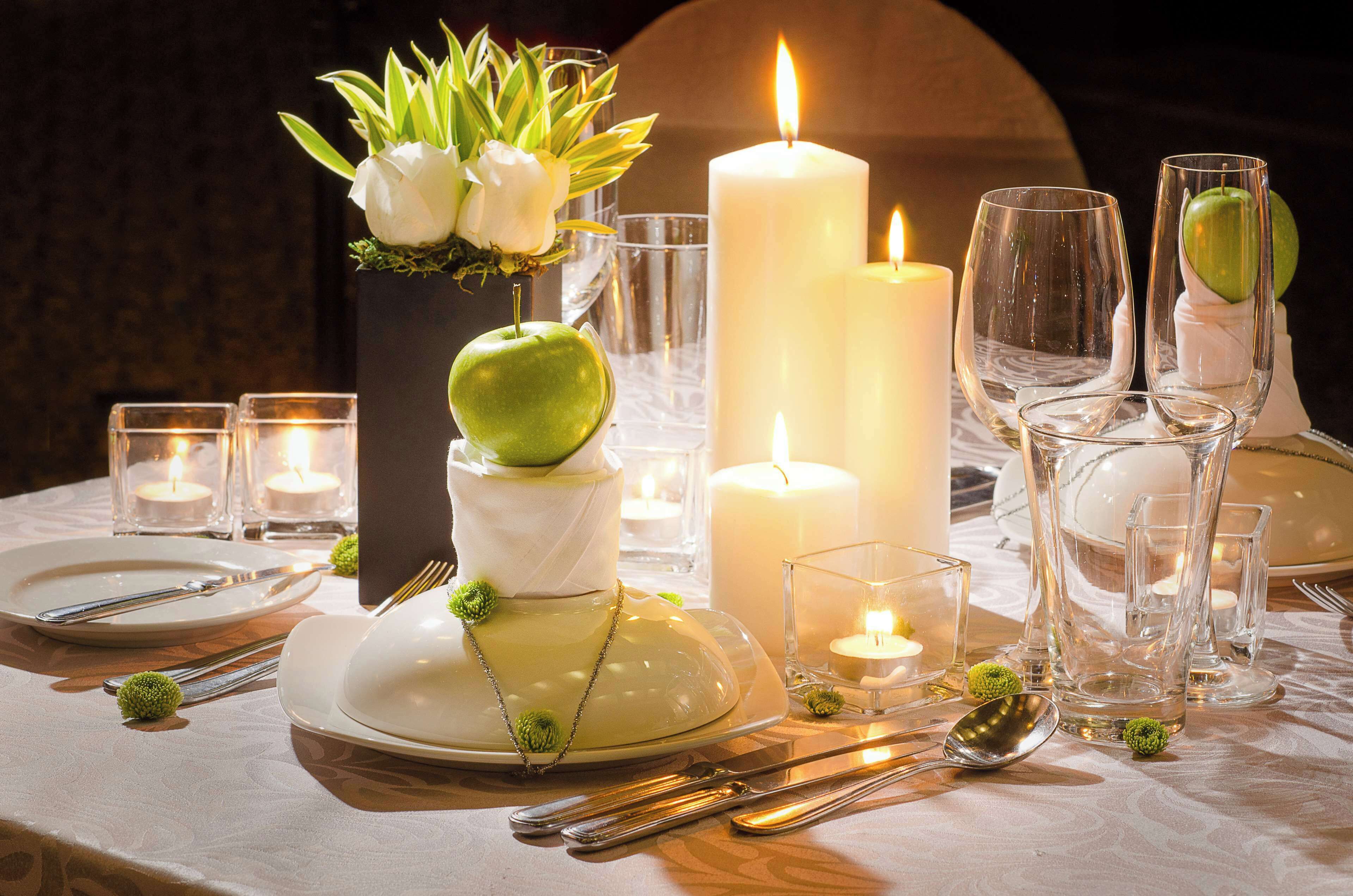 Mesa dispuesta para una cena formal, con platos blancos, cubiertos y cristalería transparente.