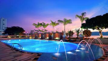 Relax by the pool surrounded by palm trees and lounge chairs.