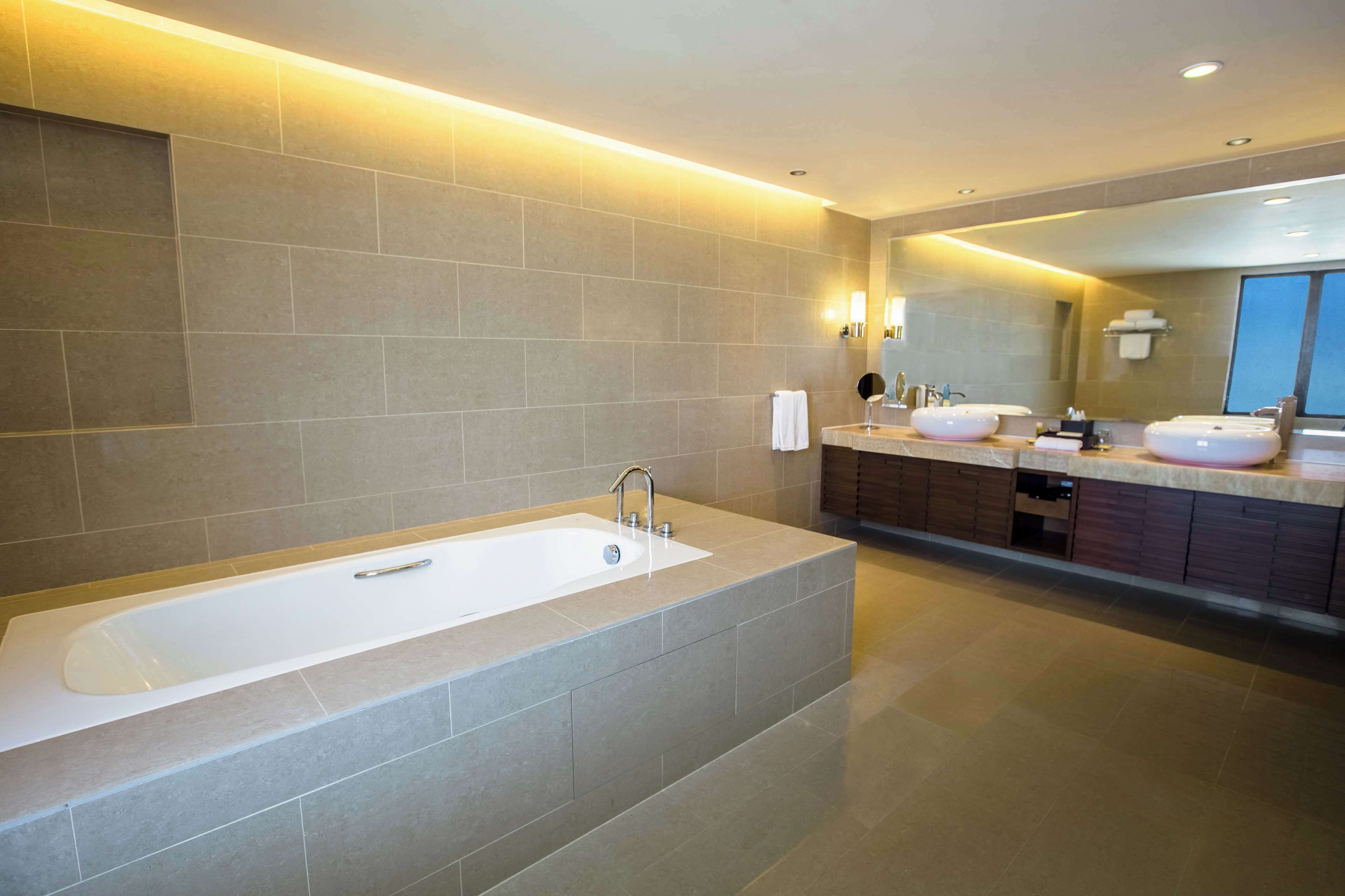 A modern bathroom with a large bathtub, two sinks, and a vanity area.