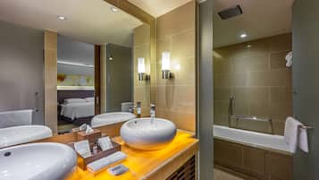 A modern bathroom with two sinks, a large mirror, and a bathtub.