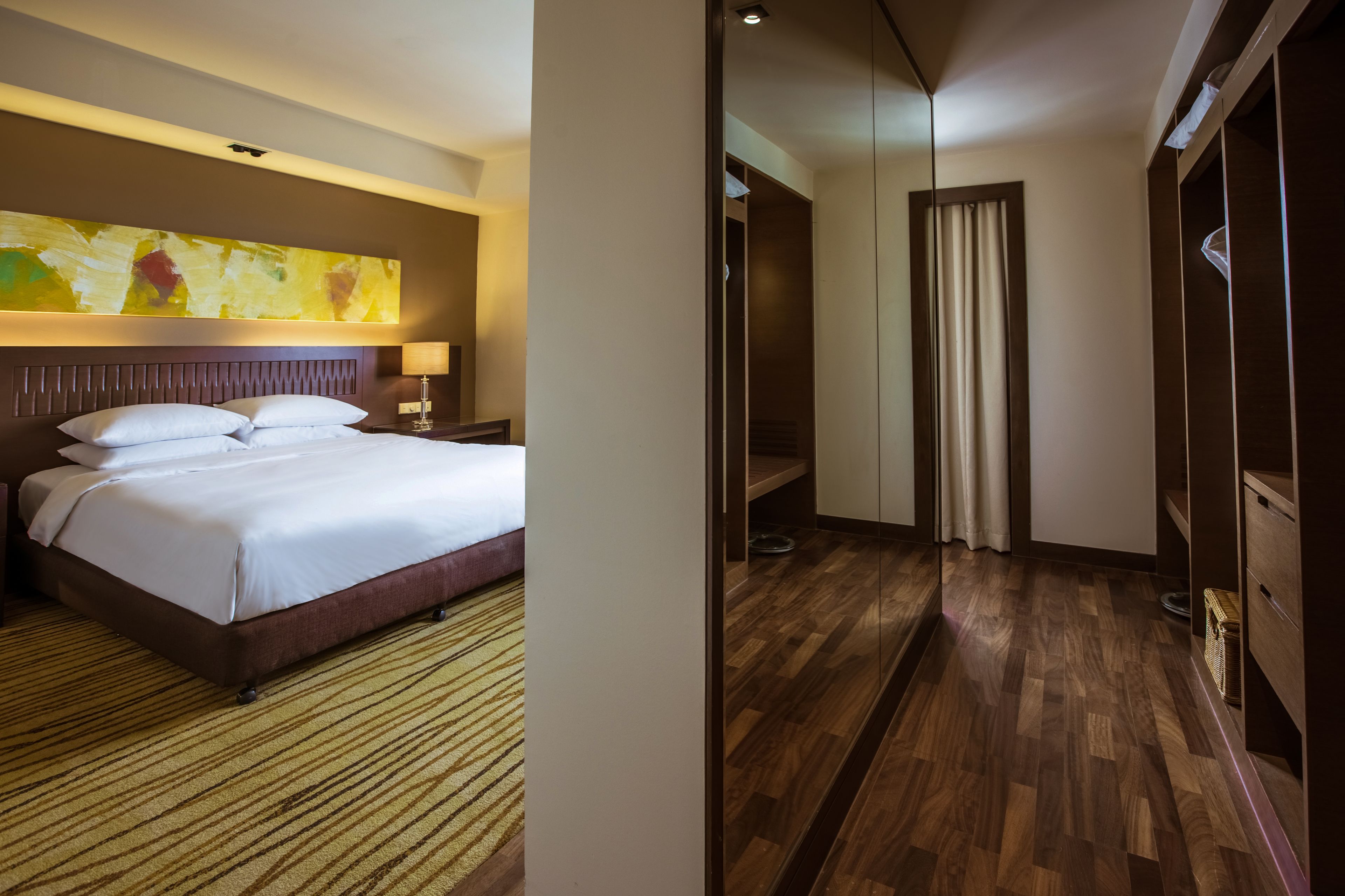 Ein Hotelzimmer mit einem großen Bett, Holzboden, einem Kleiderschrank und einem Gemälde an der Wand.
