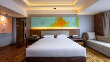 Een hotelkamer met een groot bed, twee nachtkastjes, een bank en een groot abstract schilderij aan de muur.