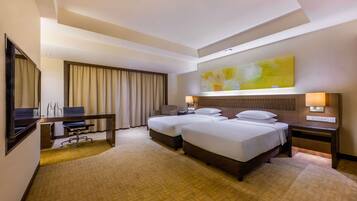 A hotel room with a large bed, a desk, a chair, and a TV.