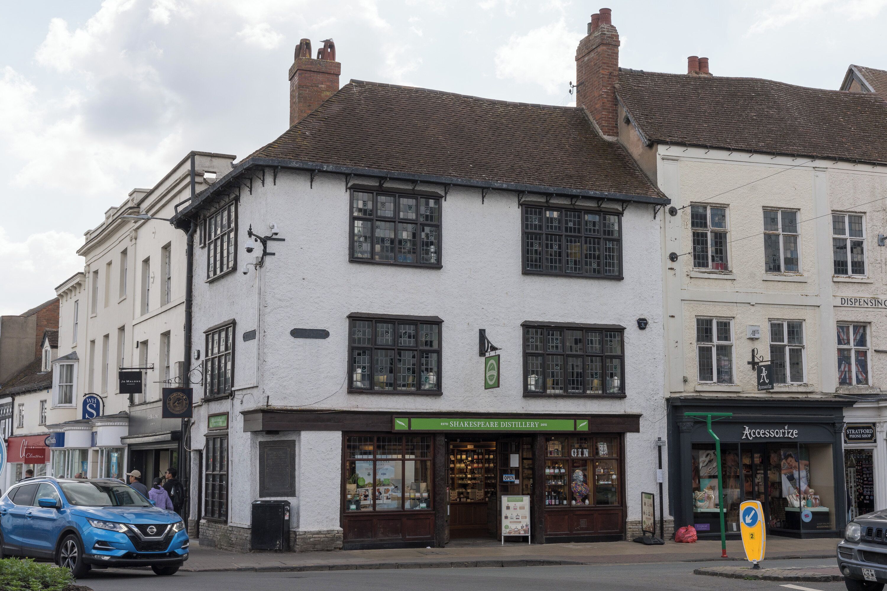 Un edificio tradicional con varias tiendas, incluyendo una destilería Shakespeare y una tienda de telefonía.