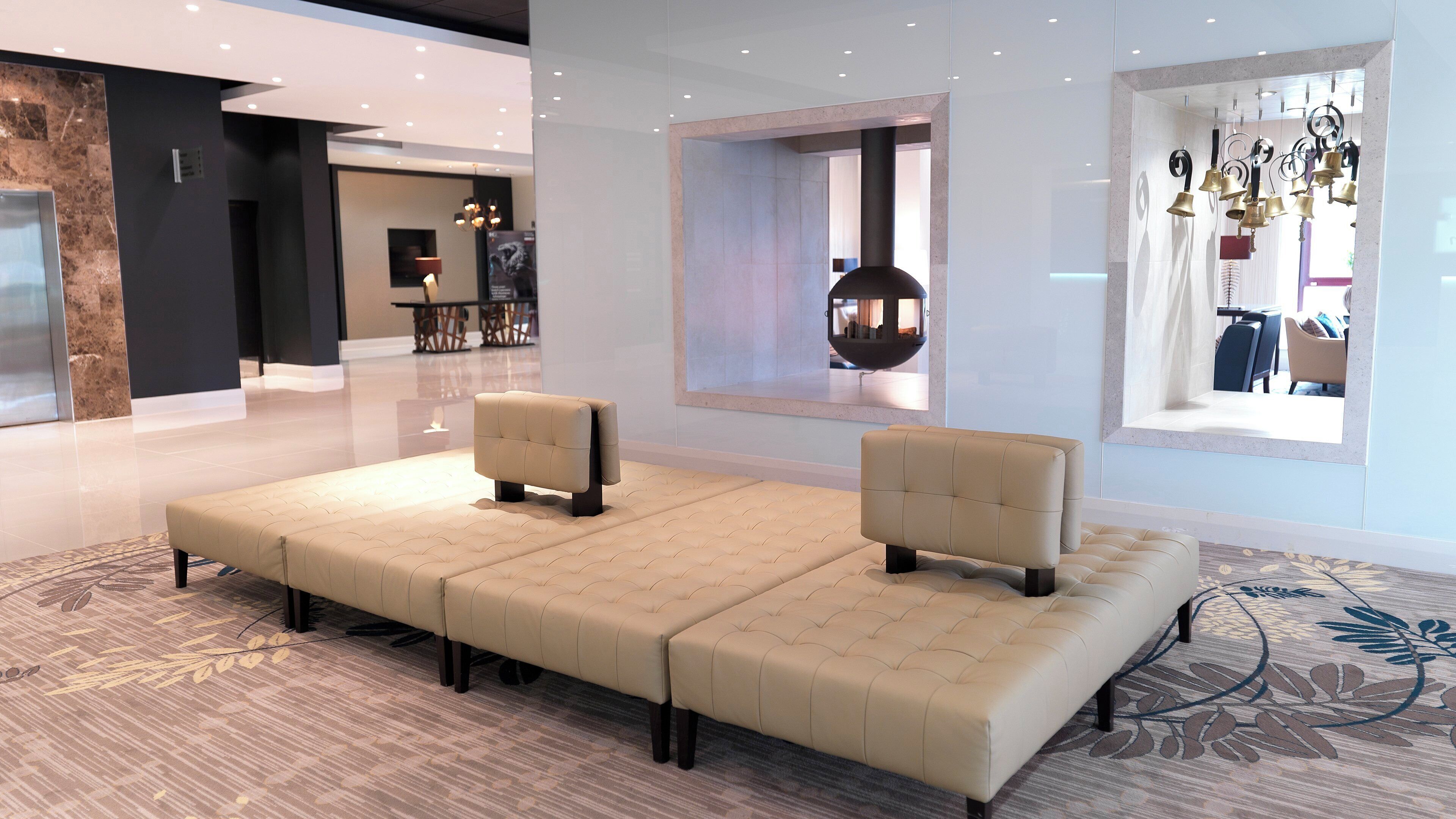 A modern hotel lobby with a large seating area, a dining area, and a view of the city.