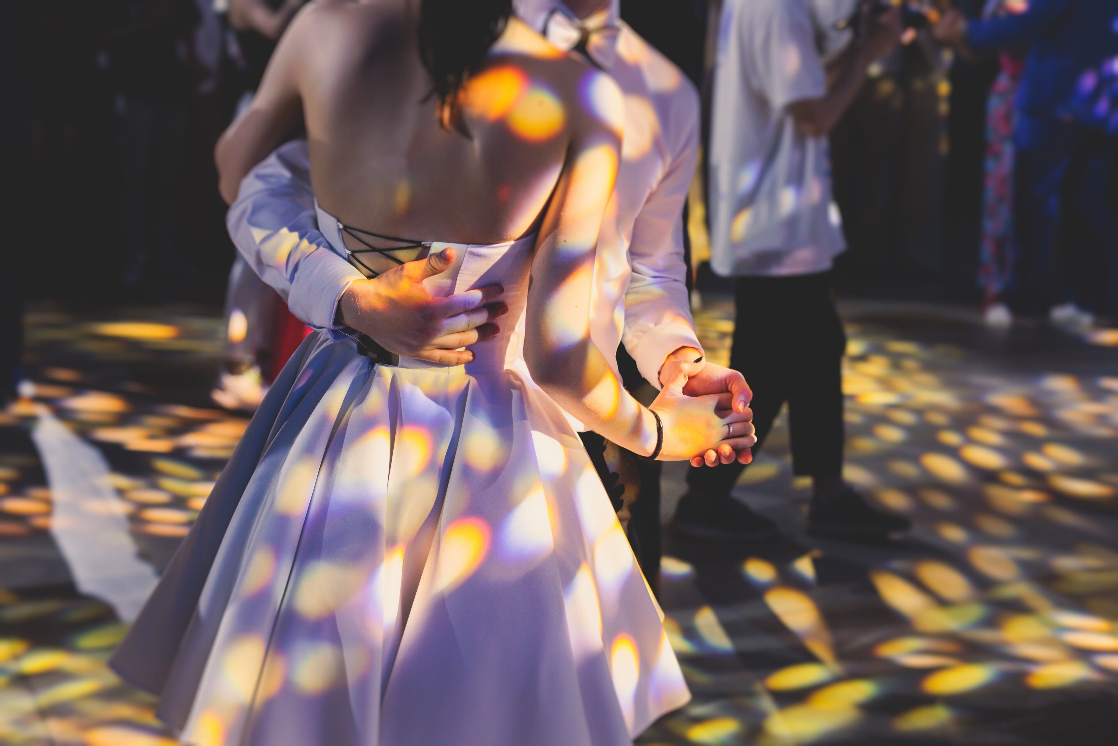 A couple dancing on a patterned floor with sunlight creating lens flares.