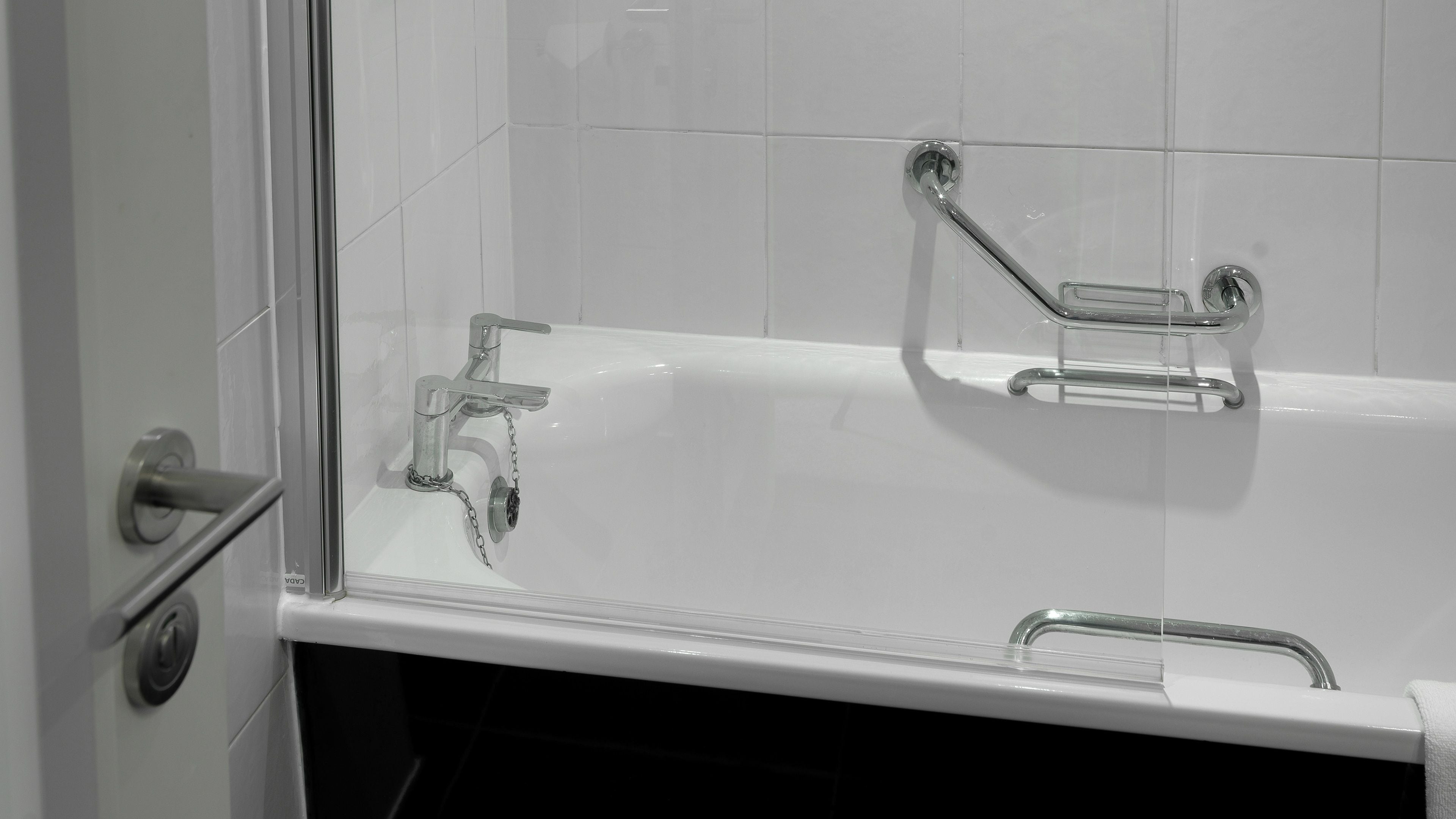 A white bathtub with a chrome faucet and two chrome grab bars.