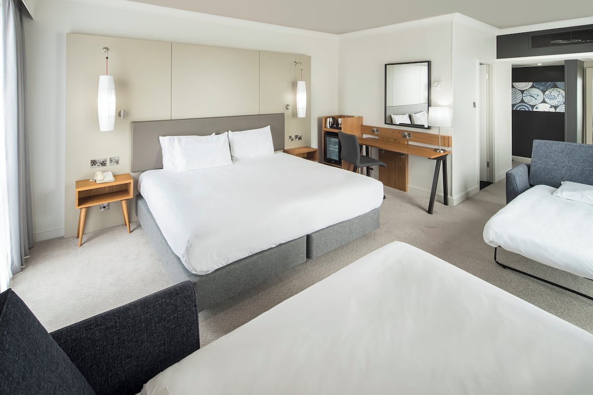 A hotel room with a large bed, a desk, a chair, and a separate couch.