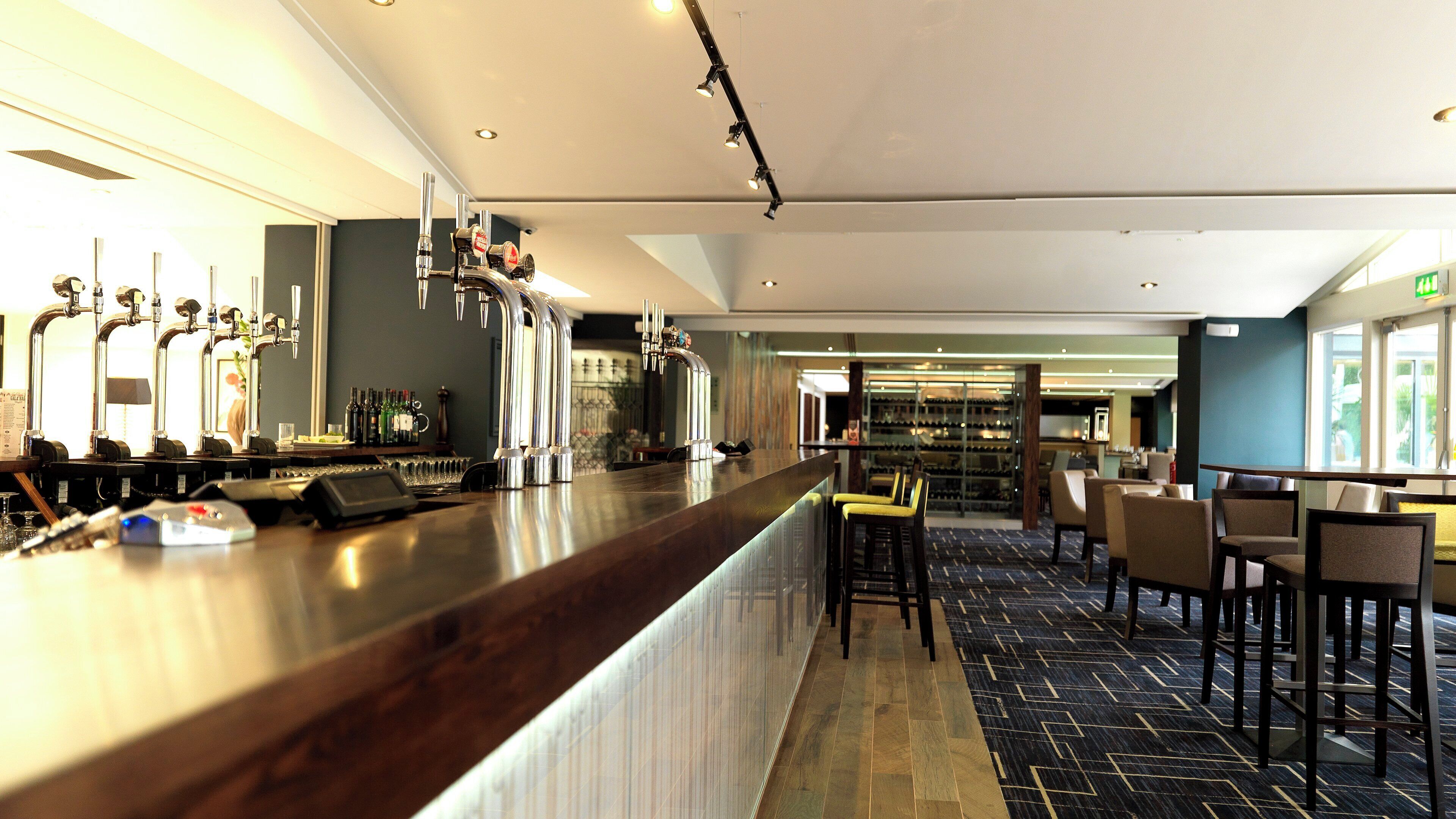 A bar area with multiple taps and a wine rack in the background.
