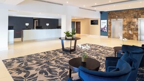 A modern lobby with a reception desk, seating area, and an elevator.
