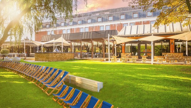 A hotel courtyard with rows of blue lounge chairs and outdoor seating areas.