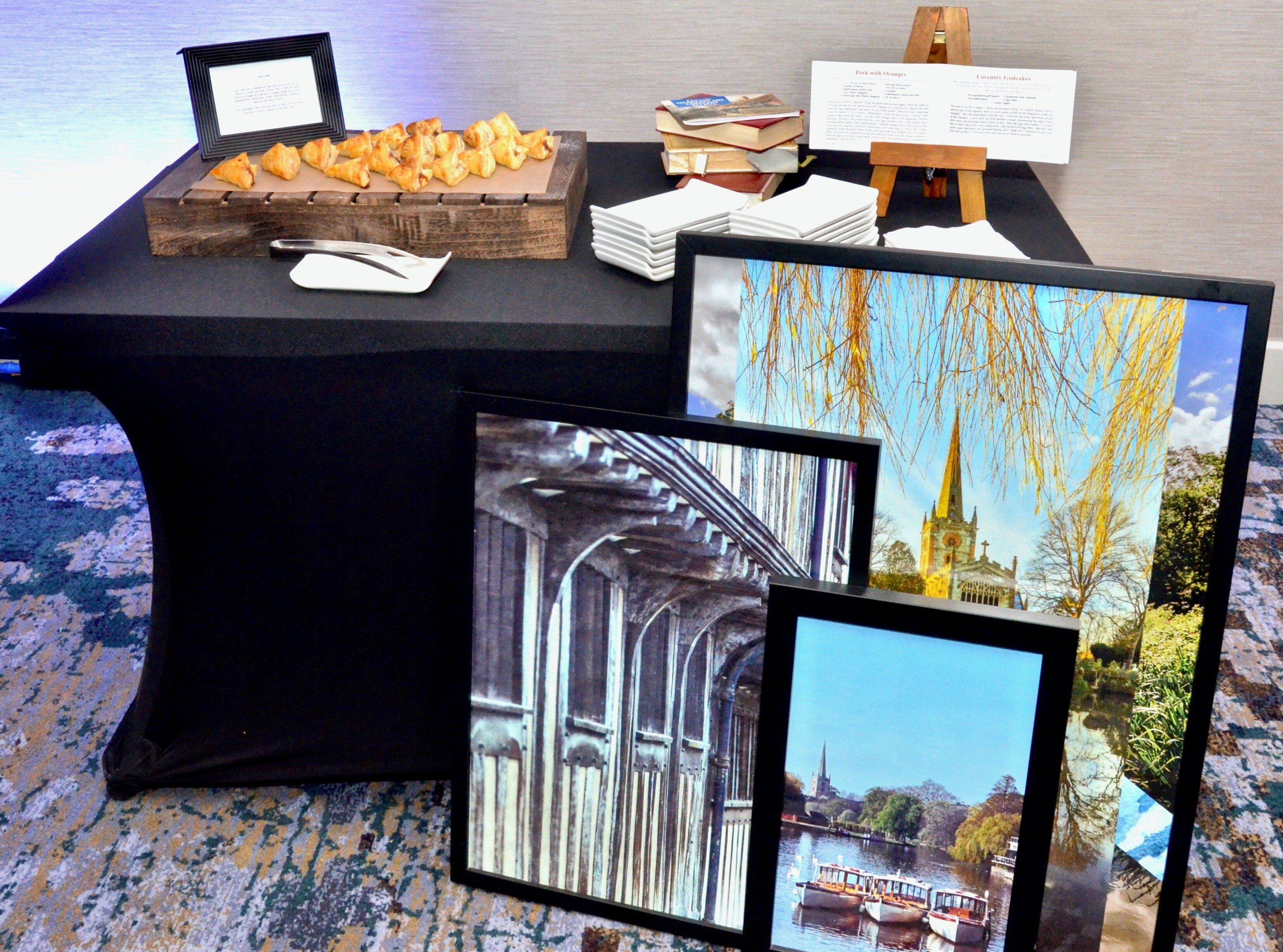 Une table avec des pâtisseries, des livres et des photos encadrées.