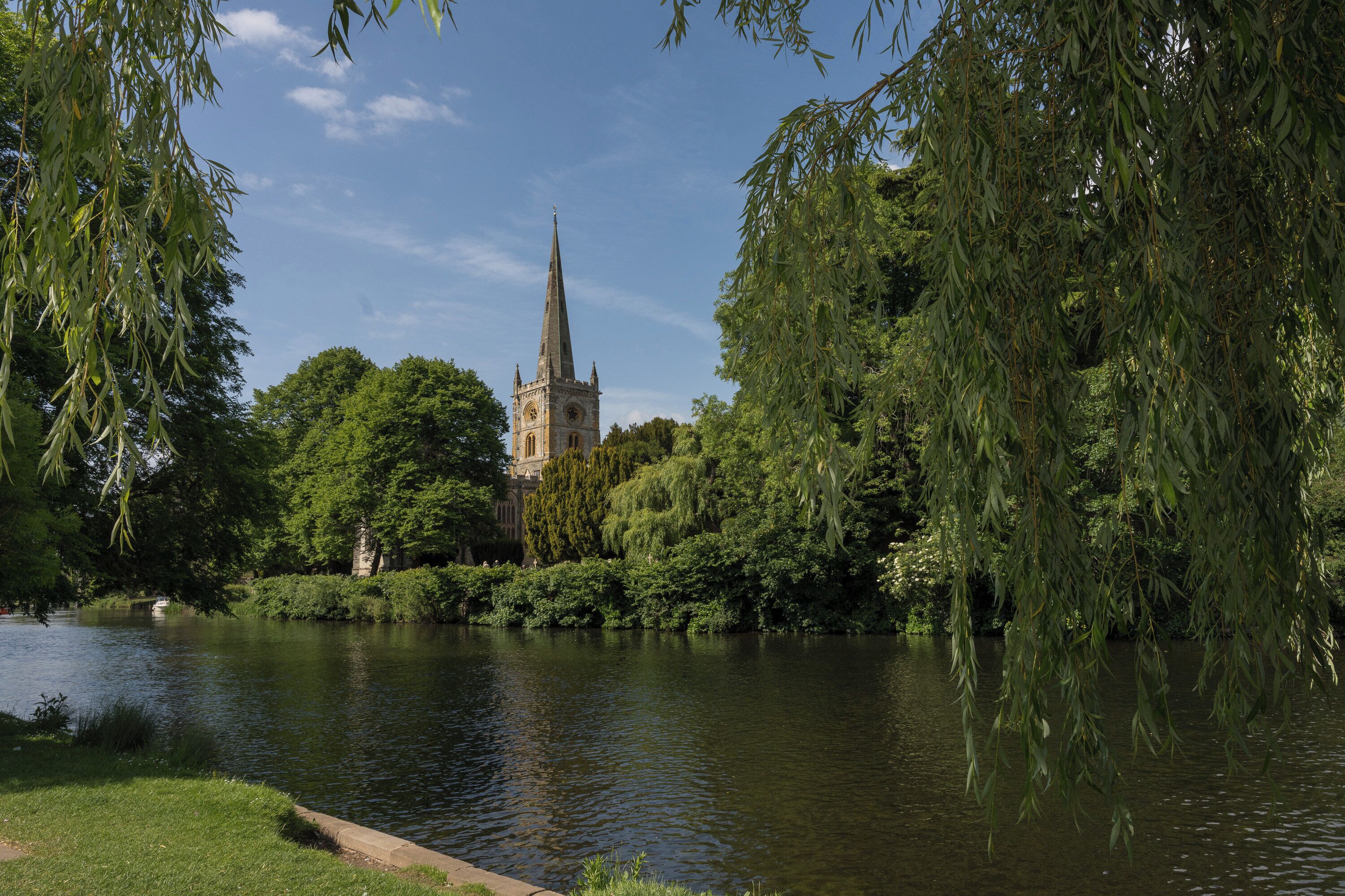 A serene riverside view with a historic church and lush greenery.