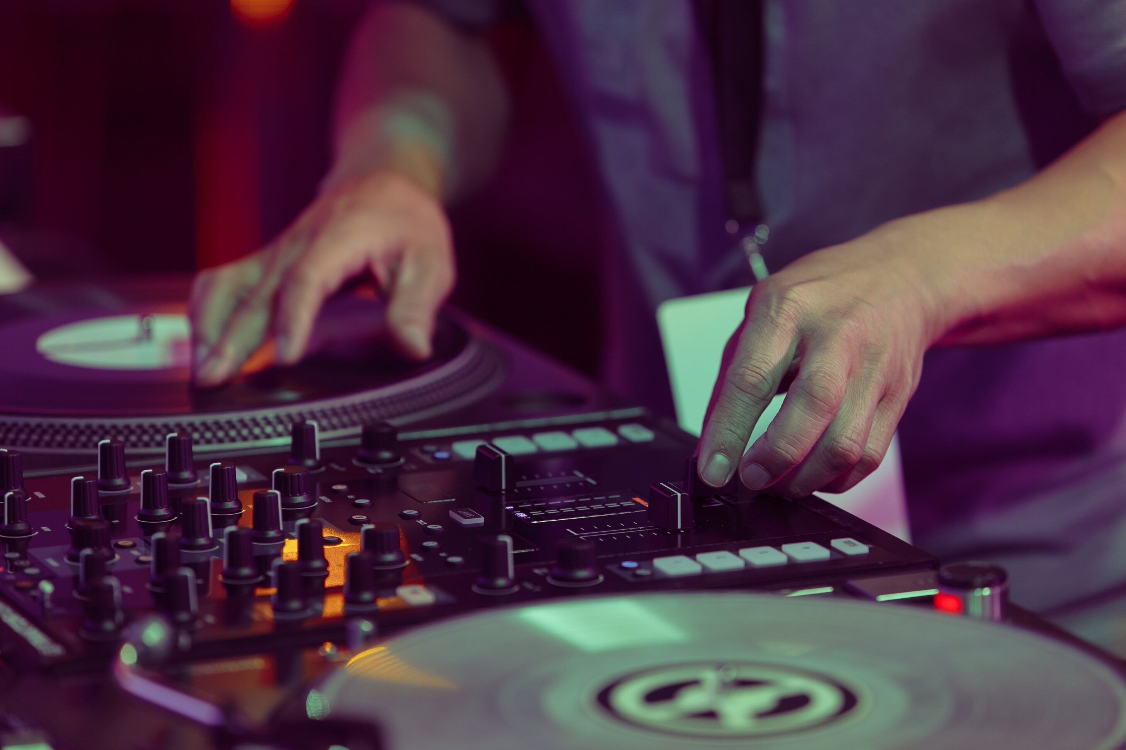 A close-up of a DJ mixing with a turntable and mixer.
