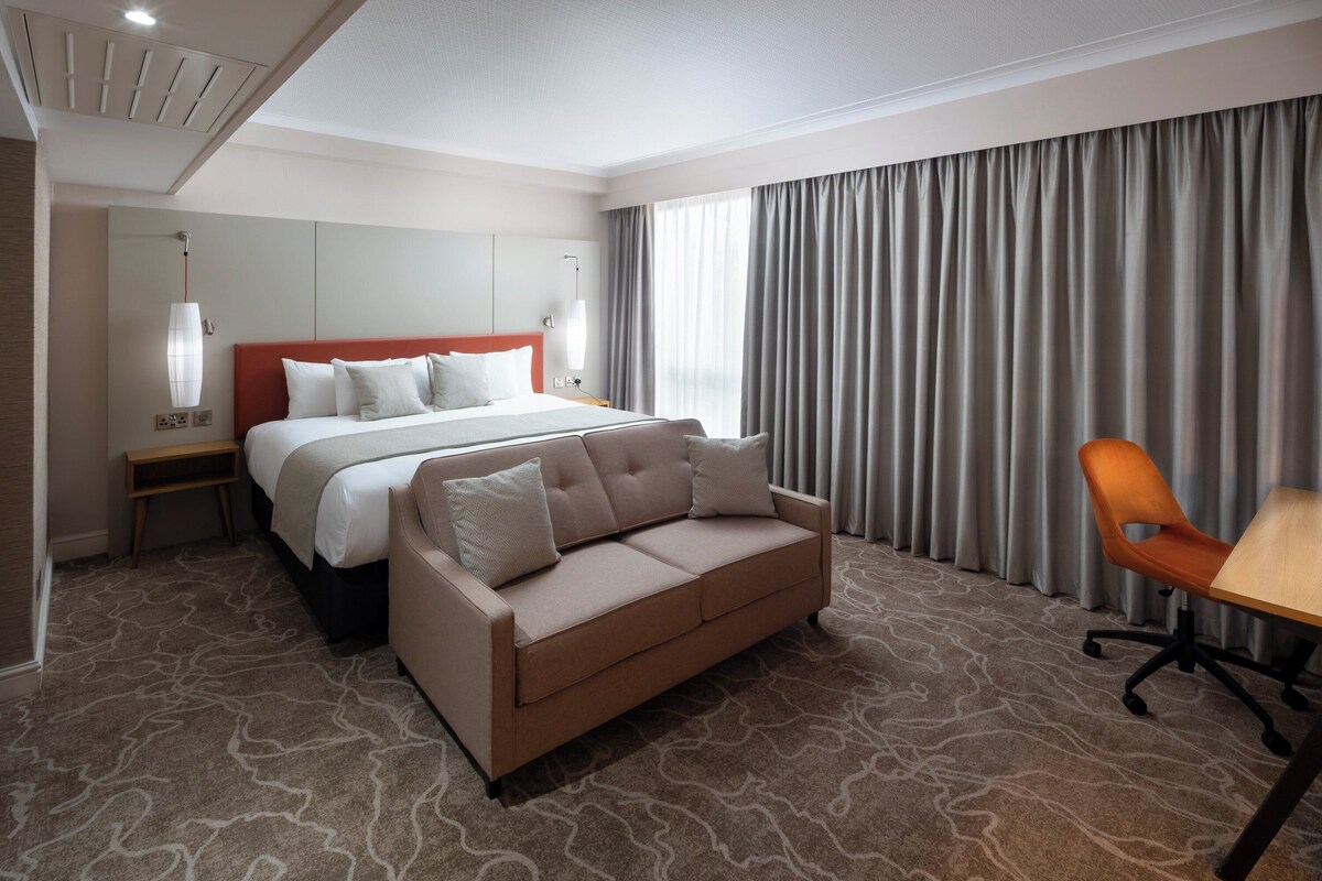 Una habitación de hotel con cama, sofá, escritorio y una silla.