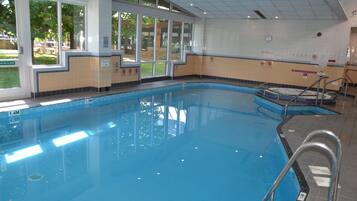 Une piscine intérieure dont la profondeur est clairement indiquée, avec un panneau interdisant de plonger, et qui offre une vue sur l’extérieur grâce à de grandes fenêtres.
