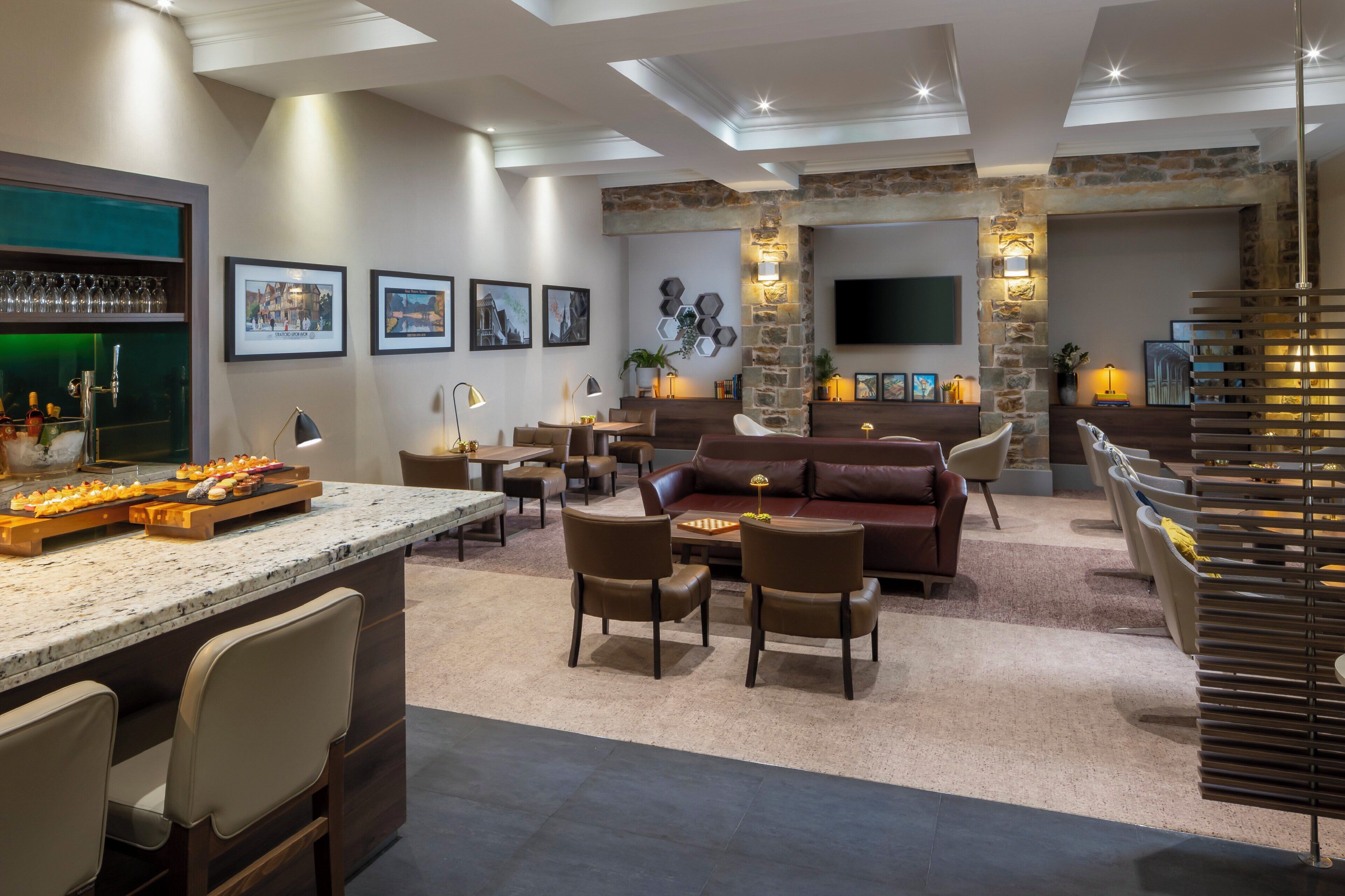 A spacious living area with a stone fireplace, comfortable seating, a bar area, and artwork on the walls.