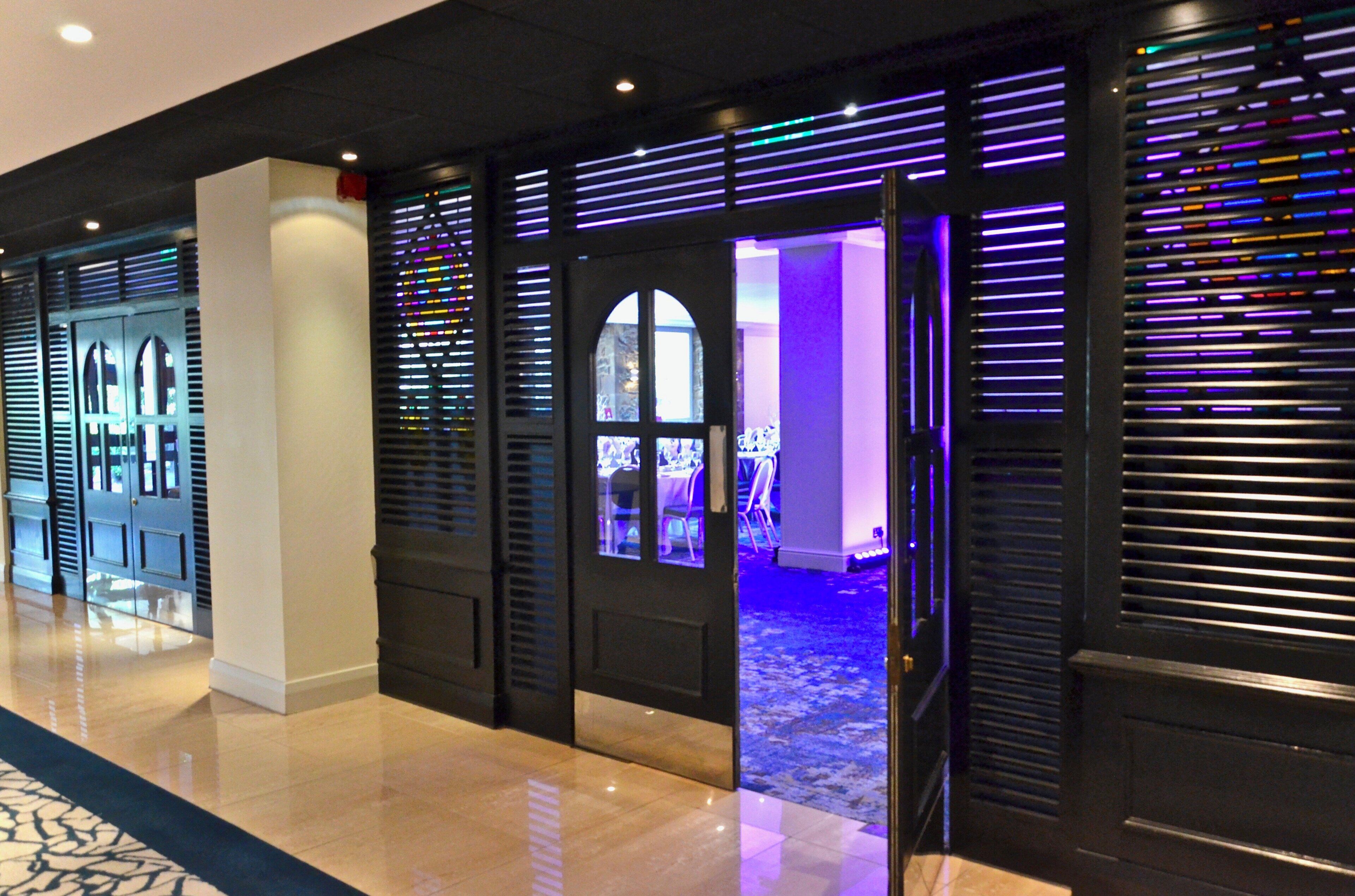 A hotel corridor with a modern design, featuring a combination of doors and windows with horizontal blinds.