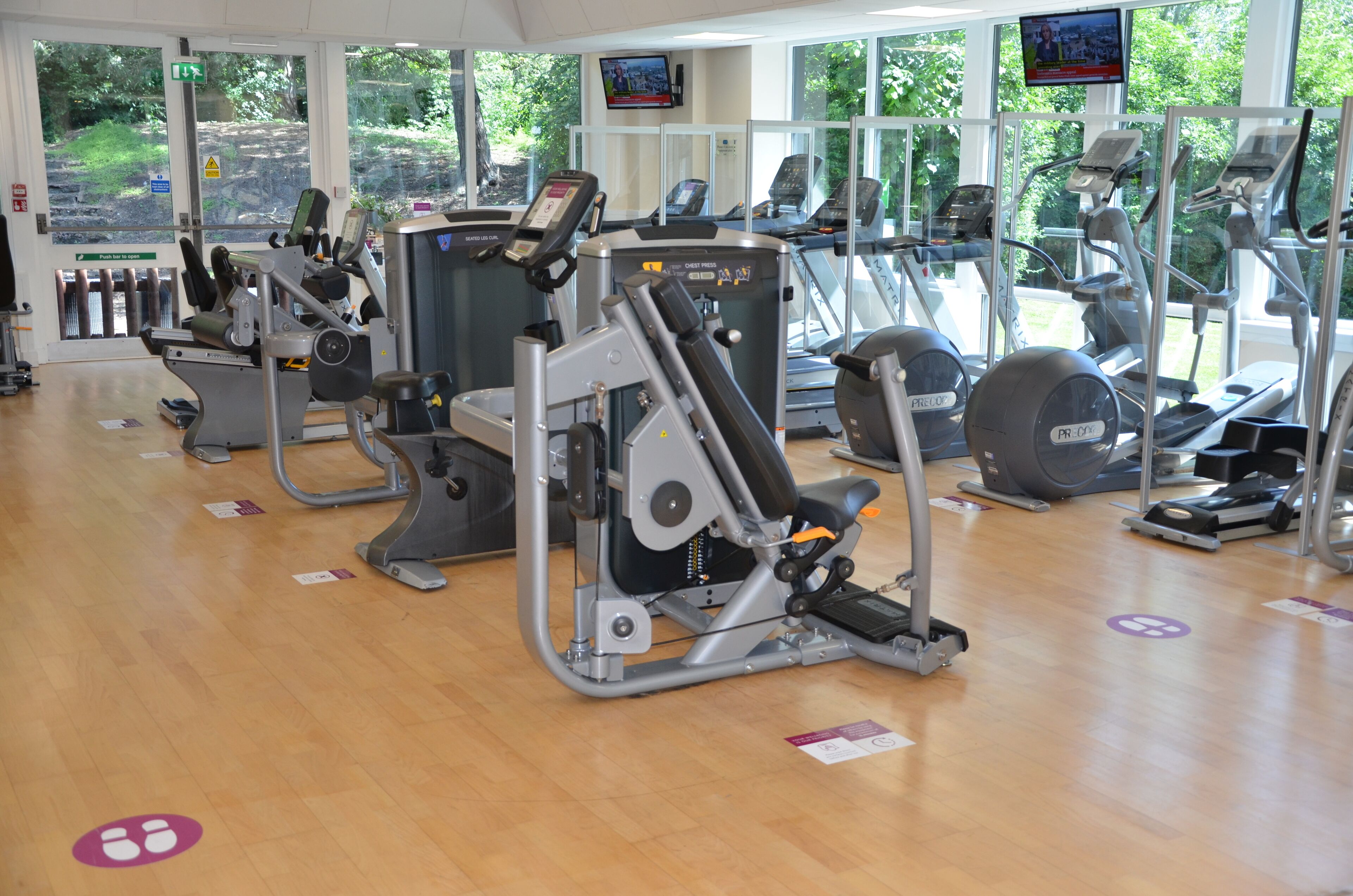 A gym with cardio machines, weight machines, and a TV screen.