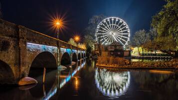 A nighttime view of a bridge with a Ferris wheel in the background.