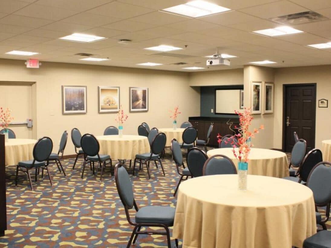 A conference room with round tables, chairs, and a projector screen.