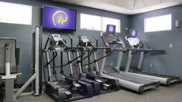 Un gimnasio con cintas de correr, elípticas y una bicicleta estática.