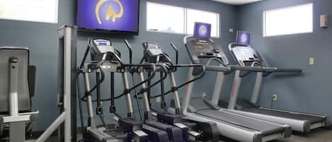 Un gimnasio con cintas de correr, elípticas y una bicicleta estática.