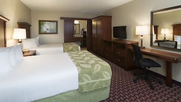 A hotel room with two beds, a desk, a chair, a television, and a mirror.