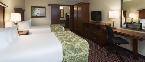 A hotel room with two beds, a desk, a chair, a television, and a mirror.